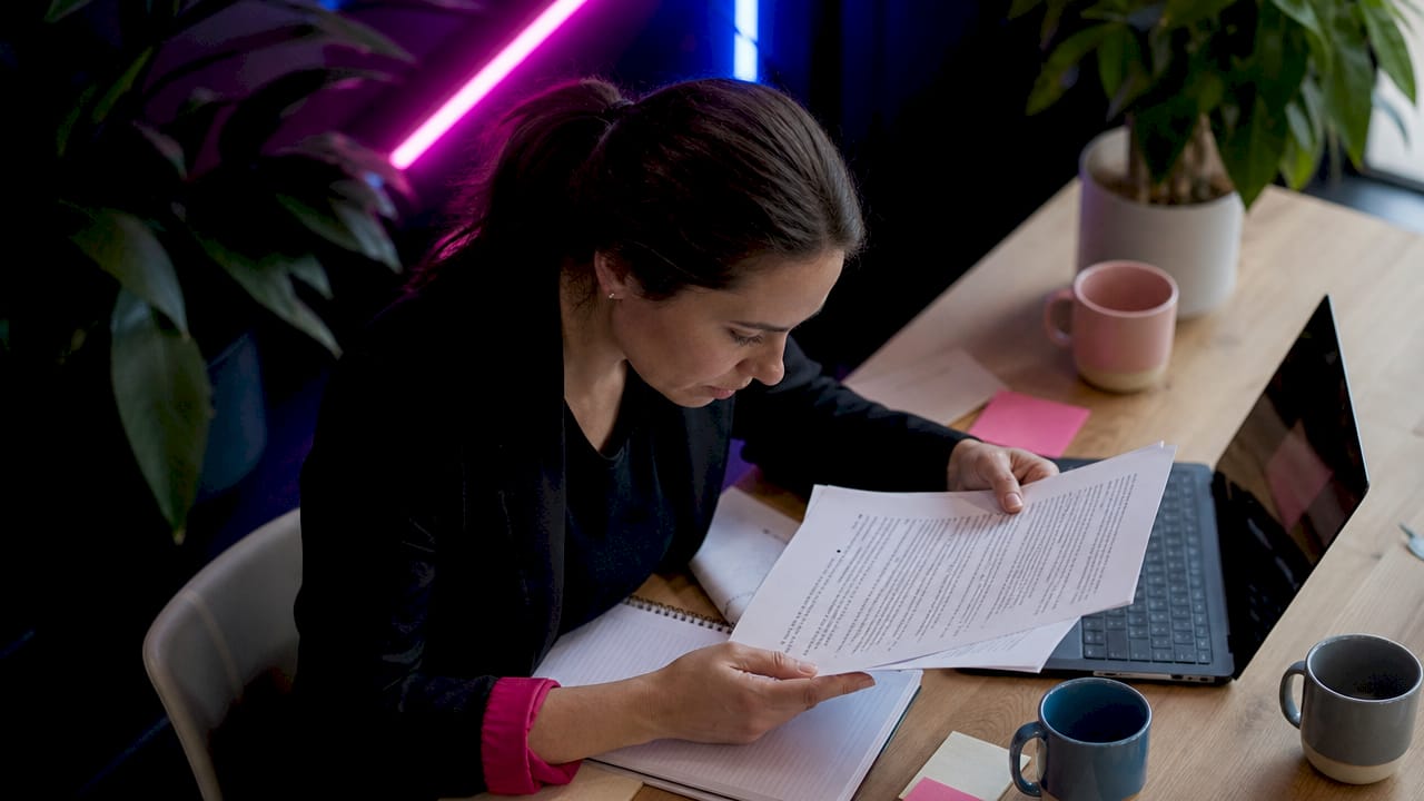 Une femme parcourt attentivement un guide imprimé sur la sécurité en ligne.