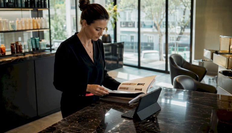 Le responsable du salon passe en revue les documents relatifs à la distribution des produits Kérastase.