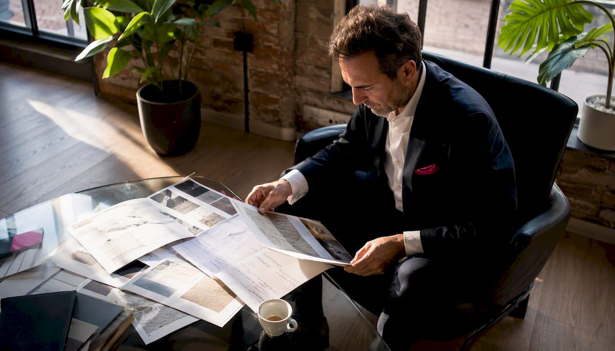 1785735177405businessmanreviewingwholesalecatalogsinoffice | Webstart Un chef d’entreprise passe en revue plusieurs catalogues de vente en gros, installé dans son bureau.